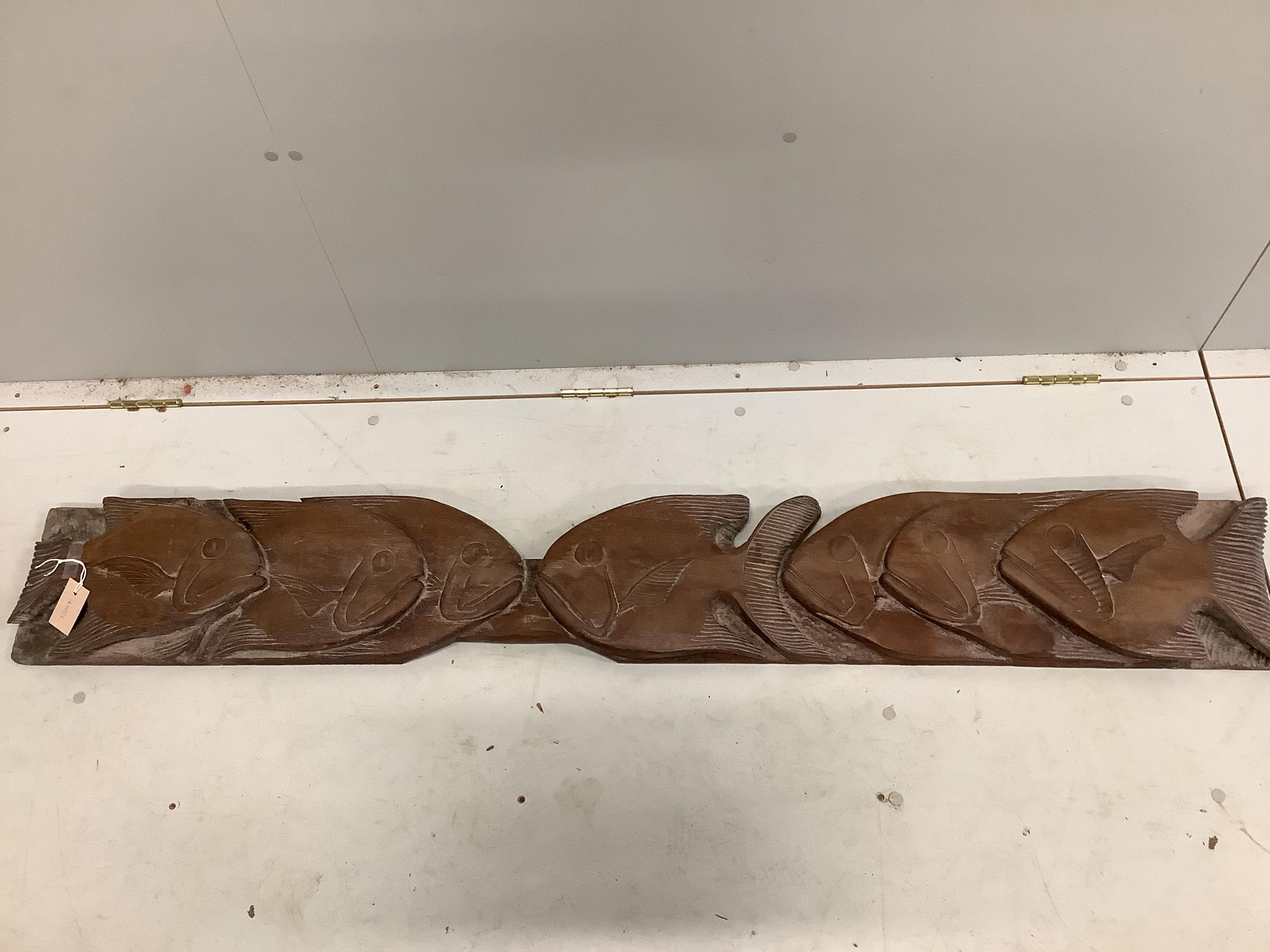 A carved wood panel of piranha fish, length 166cm